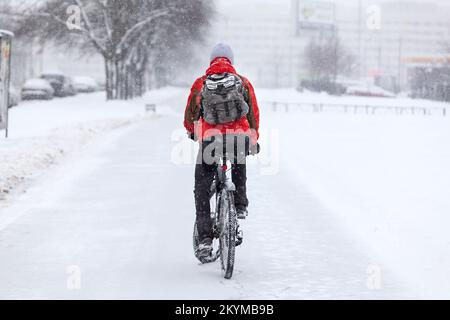 Ein Mann fährt Fahrrad auf einem Winterweg, Rückansicht Stockfoto