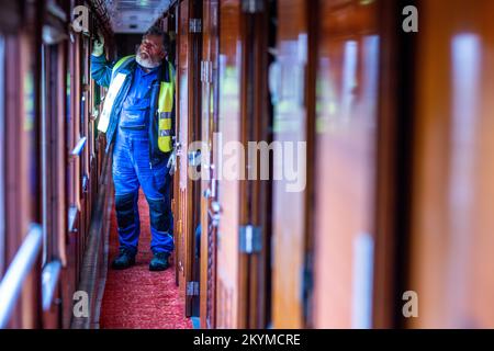 01. Dezember 2022, Mecklenburg-Vorpommern, Gadebusch: Im Gang des Schlafwagens 1941 des legendären Orient Express, der jetzt auf der Museumsstrecke neben dem historischen Bahnhof geparkt ist, steht ein Mitarbeiter eines Kranunternehmens. Der 54-Tonnen-Wagen wurde einst zwischen Paris und Istanbul von zwei auf Lkw montierten Kränen in der Nacht von der Deutschen Bahn in das Museumsviertel gehoben. Foto: Jens Büttner/dpa Stockfoto