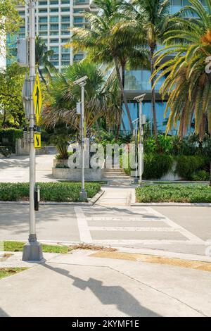 Fußgängerübergang mit gelben Schildern auf dem Pfosten an der Seite in Miami, Florida. Fußgängerübergang mit Hinweisschildern, die zu einem Gehweg in der Nähe der Büsche und Bäume am führen Stockfoto