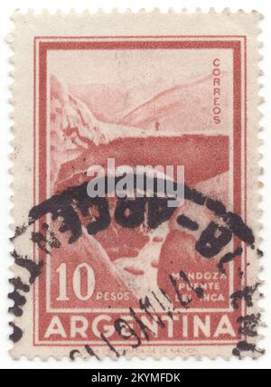 ARGENTINIEN - 1960: 10 Pesos hellrot-braune Briefmarke mit Inka-Brücke, Mendoza. Puente del Inca (englische „Brücke der Inka“) ist ein natürlicher Bogen, der eine Brücke über den Fluss Las Cuevas, einen Nebenfluss des Mendoza River, bildet. Es liegt in der Nähe des kleinen Dorfes Puente del Inca, im Las Heras Department, Mendoza Province, Argentinien. Die nahe gelegenen heißen Quellen heißen auch Puente del Inca. Puente del Inca hat zwar Anzeichen einer Verschlechterung gezeigt, bleibt aber unter den gegenwärtigen Bedingungen stabil Stockfoto