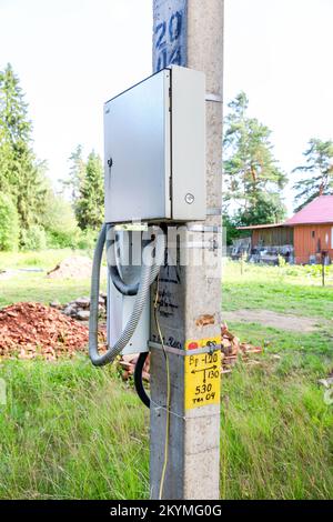 Elektrische Verteilungsplatine auf einem Netzleitungsträger im Sommer. Elektrischer Anschlusskasten am Pfosten Stockfoto