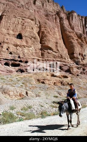 Bamyan (Bamiyan) / Zentralafghanistan: Ein kleiner Junge reitet auf einem Esel in der Nähe der Klippen in Bamyan Stockfoto