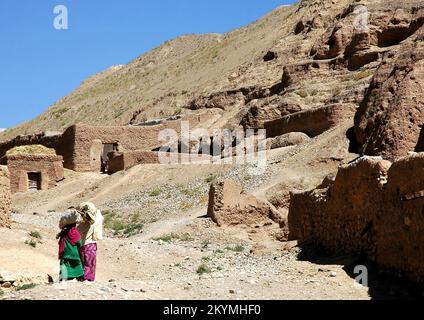 Bamyan (Bamiyan) in Zentralafghanistan. Eine Frau und ein Mädchen tragen Waren auf dem Kopf, während sie in der Nähe der Bamyan Buddhas nach Hause laufen. Stockfoto