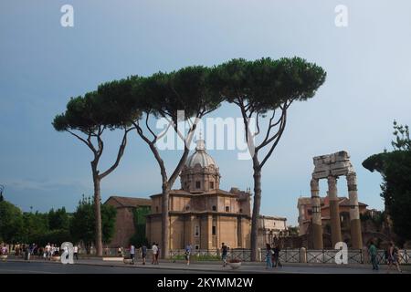 Rom, Italien - Blick auf Curia Julia und den Tempel der Venus Genetrix von der Straße. Vor dem Forum Romanum, dem politischen Zentrum des antiken Roms. Leute auf dem Bürgersteig. Stockfoto