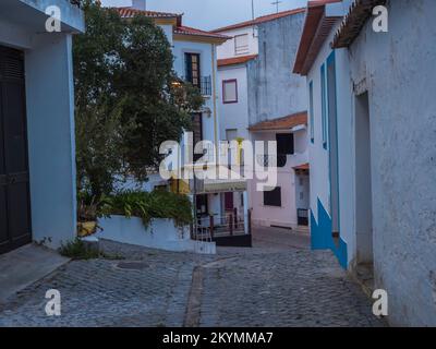 Odeceixe, Odemira, Portugal, 28. Oktober 2021: Gepflasterte Straße im Dorf Odeceixe mit alten weißen Häusern im traditionellen portugiesischen Stil, Herbstabend Stockfoto