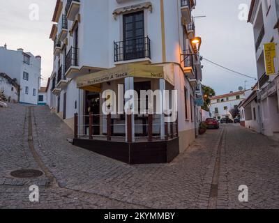 Odeceixe, Odemira, Portugal, 28. Oktober 2021: Gepflasterte Straße im Dorf Odeceixe mit alten weißen Häusern im traditionellen portugiesischen Stil, Herbstabend Stockfoto
