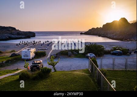 Fantastischer Sandstrand Skinaria bei Sonnenuntergang oder Dämmerung mit geparkten Autos. Abendlicher Blick auf den wunderschönen Skinaria Strand mit Autos und Wohnmobil auf dem Parkplatz Stockfoto