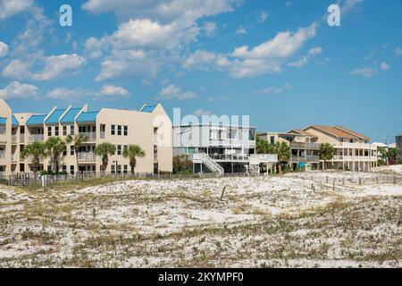 Gräser auf weißen Sanddünen in der Nähe der umzäunten Wohngebäude gegen den Himmel in Destin, FL. Es gibt eingezäunte weiße Sanddünen vorne in der Nähe Stockfoto