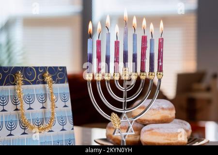 Kerzen für Chanukka gegen Chanukkiah Menorah verschwommene Hintergrundbeleuchtung Unschärfe-Licht Stockfoto