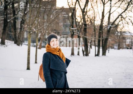 Eine Frau in warmer Winterkleidung schaut in die Kamera und lächelt im Winter Stockfoto