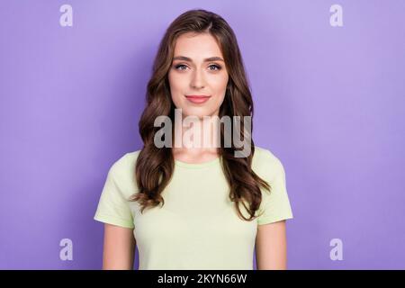 Foto von gut aussehender hübscher junger bezaubernder Frau Trag weißes T-Shirt seidig geschwungene Frisur, auf die du dich konzentriert hast, isoliert auf violettem Hintergrund Stockfoto