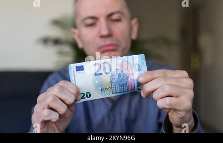 Weißer Mann, der seine 20-Euro-Banknote sieht Stockfoto