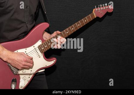 Vaduz, Liechtenstein, 11. Januar 2022 Musiker spielt einen Fender Stratocaster USA Crafted 1995 in der Farbe Burgunder Nebel Stockfoto