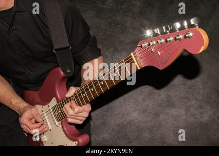 Vaduz, Liechtenstein, 11. Januar 2022 Musiker spielt einen Fender Stratocaster USA Crafted 1995 in der Farbe Burgunder Nebel Stockfoto