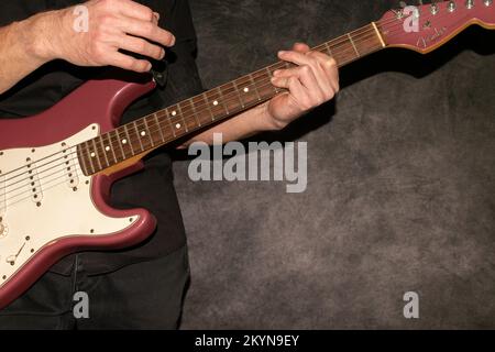 Vaduz, Liechtenstein, 11. Januar 2022 Musiker spielt einen Fender Stratocaster USA Crafted 1995 in der Farbe Burgunder Nebel Stockfoto