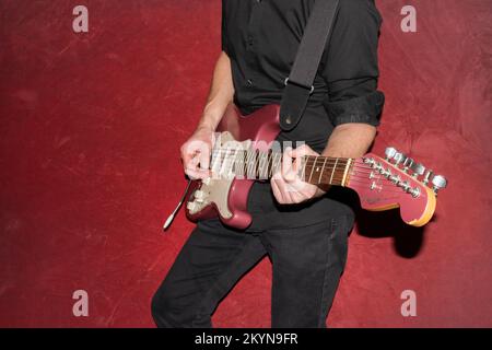 Vaduz, Liechtenstein, 11. Januar 2022 Musiker spielt einen Fender Stratocaster USA Crafted 1995 in der Farbe Burgunder Nebel Stockfoto