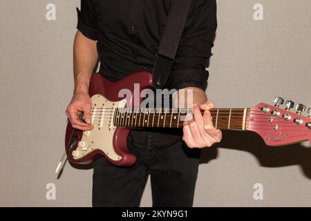 Vaduz, Liechtenstein, 11. Januar 2022 Musiker spielt einen Fender Stratocaster USA Crafted 1995 in der Farbe Burgunder Nebel Stockfoto