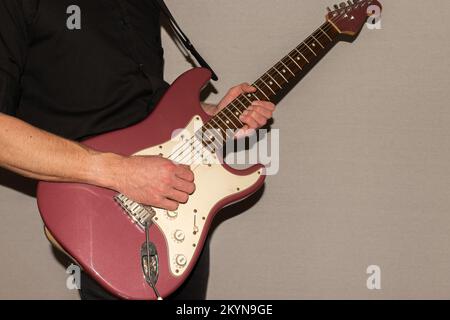 Vaduz, Liechtenstein, 11. Januar 2022 Musiker spielt einen Fender Stratocaster USA Crafted 1995 in der Farbe Burgunder Nebel Stockfoto