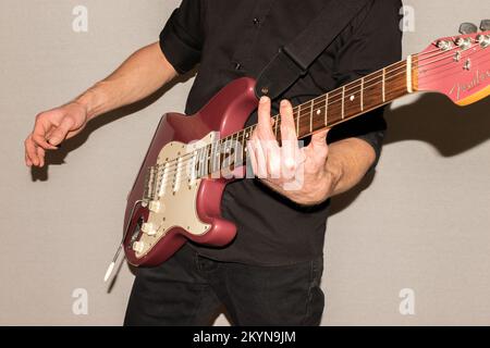 Vaduz, Liechtenstein, 11. Januar 2022 Musiker spielt einen Fender Stratocaster USA Crafted 1995 in der Farbe Burgunder Nebel Stockfoto