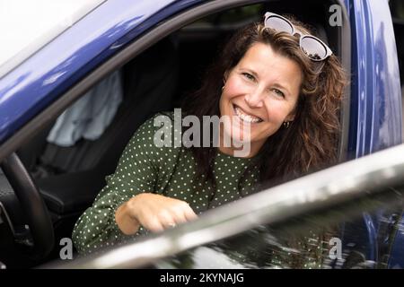 Porträt einer glücklichen Frau mit Sonnenbrille im Auto Stockfoto