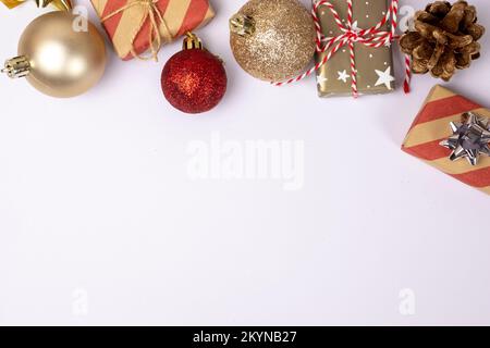 Weihnachtlicher Hintergrund mit Kopierbereich auf Weiß, Geschenkboxen, roten und goldenen Kugeln und Pinienzapfen, Draufsicht. Vorlage für Postkarten, Banner, Grußkarten Stockfoto