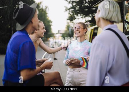 Glückliche nicht-binäre Person, die von Freunden mit einer Frau spricht Stockfoto