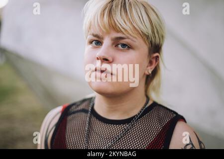 Porträt einer glücklichen jungen, nicht binären Person mit kurzen blonden Haaren Stockfoto