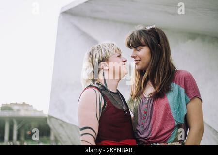 Lächelndes junges Paar, das sich an der Wand ansieht Stockfoto