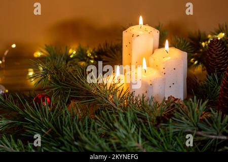 Weihnachtskerzen und Dekorationen auf dunklem Hintergrund mit Lichtern. Advent - vier lila Kerzen mit Weihnachtsschmuck. Romantisch Stockfoto