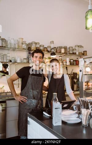 Porträt von glücklichen männlichen und weiblichen Geschäftsinhabern, die im Café zusammenstehen Stockfoto