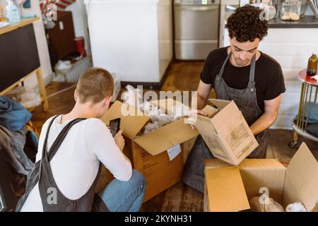 Männliche und weibliche Besitzer helfen sich gegenseitig, während sie im Café zusammenarbeiten Stockfoto