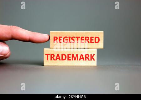 Eingetragenes Markenzeichen. Konzeptwort eingetragene Marke Holzblöcke. Wunderschöner grauer Tischhintergrund. Geschäftsmannshand. Business und reg Stockfoto