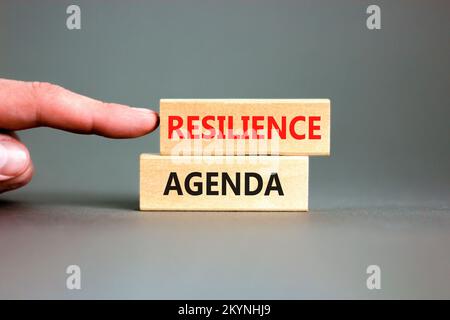 Symbol für Resilienz-Agenda. Konzeptwort „Resilience Agenda“ auf Holzblöcken getippt. Wunderschöner grauer Tischhintergrund. Geschäftsmannshand. Business und Stockfoto