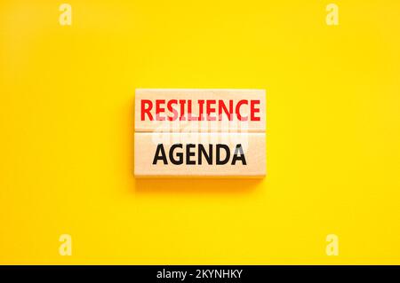 Symbol für Resilienz-Agenda. Konzeptwort „Resilience Agenda“ auf Holzblöcken getippt. Wunderschöner gelber Hintergrund für den Tisch. Unternehmen und Widerstandsfähigkeit Stockfoto