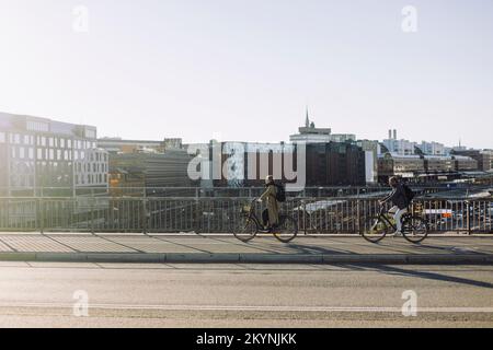 Männliche und weibliche Geschäftsleute, die Fahrräder auf der Straße benutzen Stockfoto