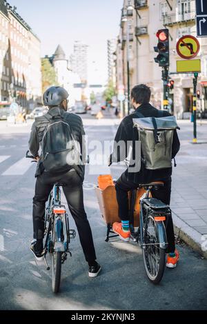 Geschäftsleute mit Cargo Bike und Fahrrad warten an der Verkehrsampel auf der Straße Stockfoto