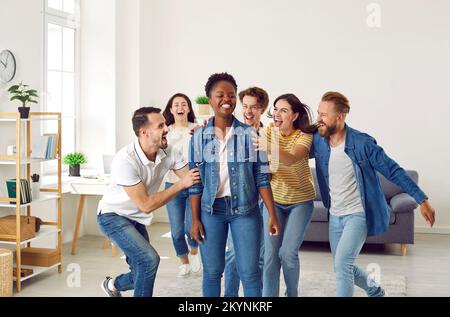 Eine Gruppe glücklicher junger Menschen, die ihren Freund zu seinem großen Erfolg beglückwünschen Stockfoto