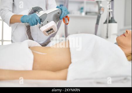 Kosmetologe, der eine Rollermassage mit maschineller Verschließung durchführt Stockfoto