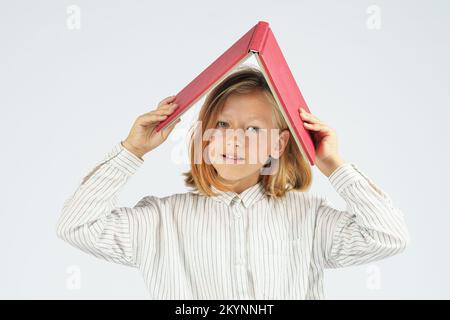 Teenager, die ein offenes Buch über ihrem Kopf hält. Isolierter Hintergrund. Bildungskonzept. Stockfoto