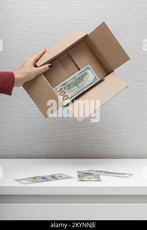 Ein Mann hält eine Kiste, in der Dollars sind Stockfoto