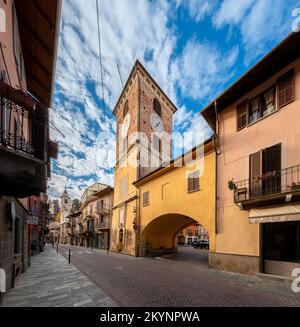 Borgo San Dalmazzo, Cuneo, Italien - 01. Dezember 2022: Via Roma mit dem im 16.. Jahrhundert erbauten Stadtturm, mit Bogen für den Zugang zum Granat Stockfoto