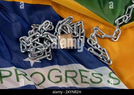 Kette, Vorhängeschloss und brasilianische Flagge symbolisieren die Sklaverei im Land Stockfoto