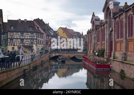 Colmar, Frankreich, Elsass, Dezember 2021. Die französische Stadt Colmar am Heiligabend. Leute auf einem Boot segeln auf dem Kanal. Farbenfrohe mittelalterliche Häuser Stockfoto