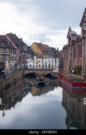 Colmar, Frankreich, Elsass, Dezember 2021. Die französische Stadt Colmar am Heiligabend. Leute auf einem Boot segeln auf dem Kanal. Farbenfrohe mittelalterliche Häuser Stockfoto