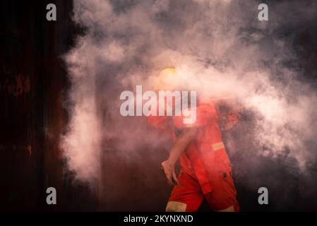 Ein Feuerwehrmann mit Ausrüstung versucht, Menschen zu helfen, die im Hausbrand gefangen sind. Stockfoto