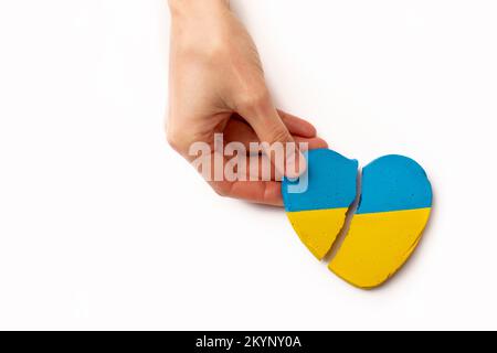 Hände halten ein gebrochenes Herz der Ukraine, Krieg auf weißem Hintergrund. Hochwertiges Foto Stockfoto