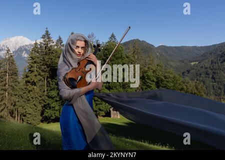 Junger Geiger, der vor dem Hintergrund der Alpen posiert Stockfoto