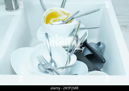 Waschbecken voll mit einem Stapel schmutzigen Geschirr. Geschirr waschen, Geschirr nach dem Essen, Essensreste. Spüle mit Löffeln, Gabeln, Messern, Tellern. War Stockfoto