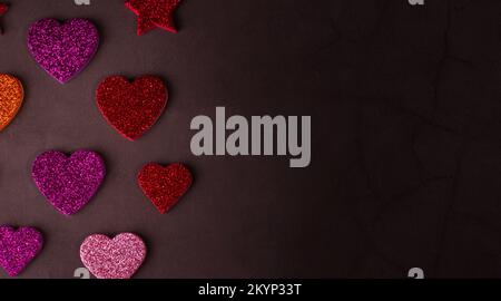 Valentinstag-Konzeptbanner mit glitzernden Herzen vor abstraktem grauen Hintergrund und dem Bokeh aus Girlande mit Platz für Text. Stockfoto