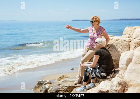 Zwei ältere Frauen freuen sich, sich am Meer zu treffen Stockfoto
